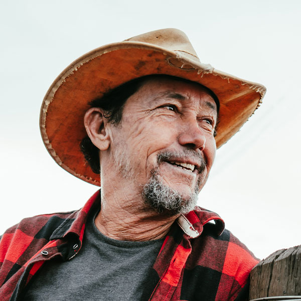 smiling man wearing a hat and flannel shirt